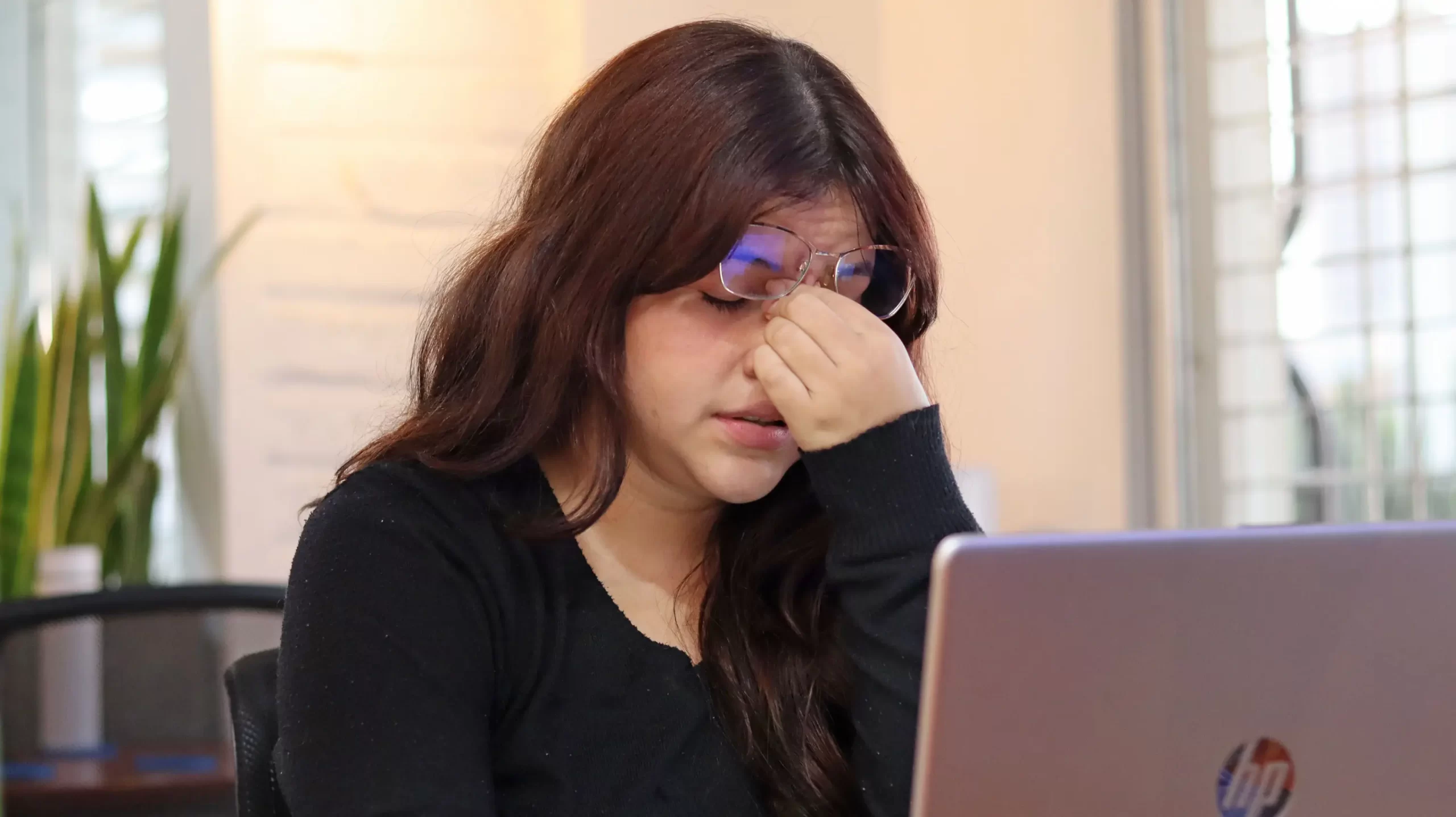 Woman overwhelmed by work on her laptop.