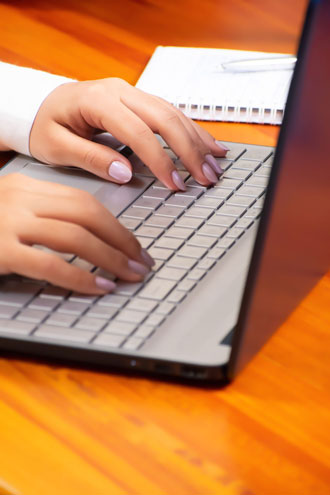 Hands typing on a laptop