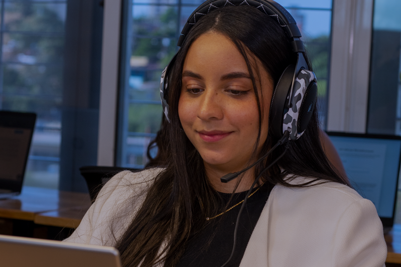 Smiling remote customer service representative from Latin America wearing a headset and working from a modern office.